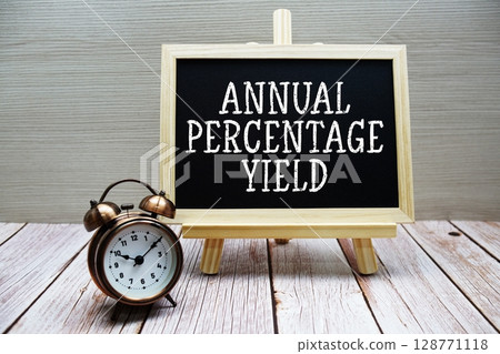 Annual Percentage Yield text written on chalkboard with alarm clock on wooden background 128771118