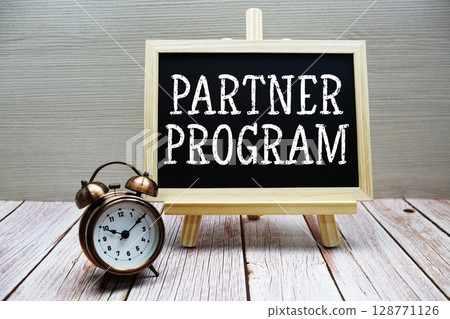 Partner Program text written on chalkboard with alarm clock on wooden background 128771126
