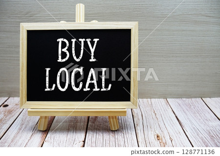 Buy Local text written on chalkboard with easel on wooden background Buy Local text written on chalkboard with easel on wooden background 128771136