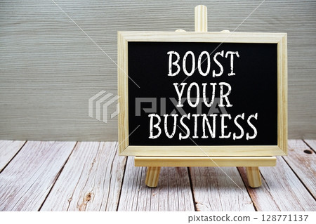 Boost Your Business text written on chalkboard with easel on wooden background 128771137
