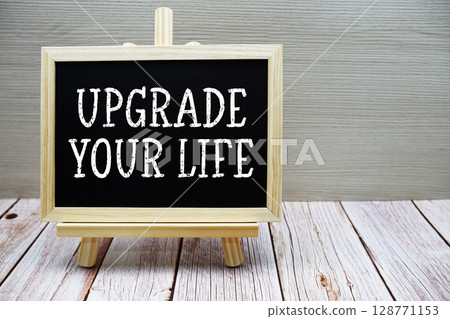 Upgrade Your Life text written on chalkboard with easel on wooden background 128771153