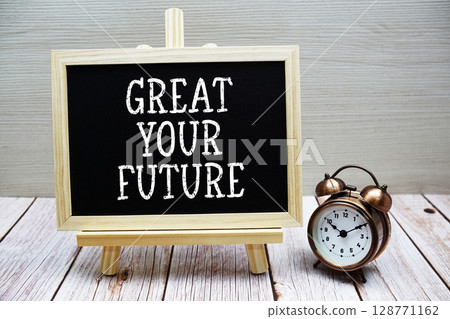 Gret Your Future text written on chalkboard with alarm clock on wooden background Gret Your Future text written on chalkboard with alarm clock on wooden background 128771162