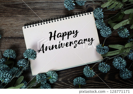 Happy Anniversary text with flowers decoration on wooden background 128771171