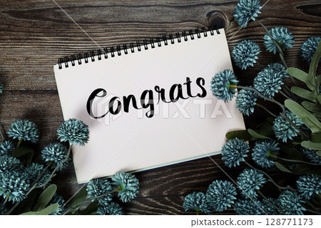Congrats text with flowers decoration on wooden background 128771173