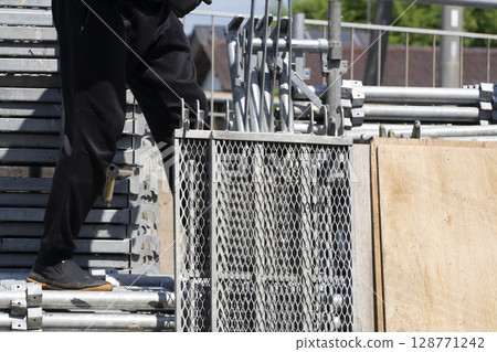 Assembling the scaffolding: Workers unloading materials from a truck and preparing them Assembling the scaffolding: Workers unloading materials from a truck and preparing them 128771242