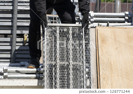 搭建鷹架：工人從卡車上卸下材料並進行準備 128771244