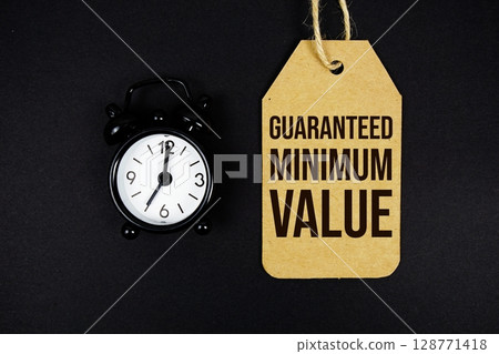 Guaranteed Minimum Value text on price tag with alarm clock on black background 128771418