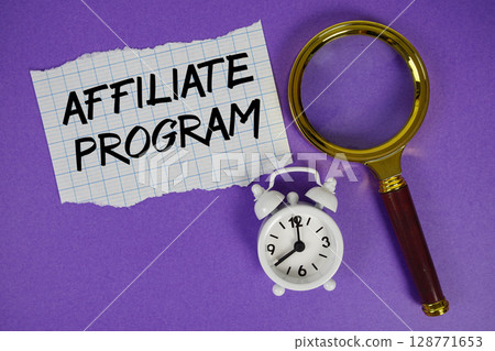 Affiliate Program text written on paper with magnifying glass and alarm clock 128771653
