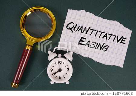 Quantitative Easing text written on paper with magnifying glass and alarm clock 128771668