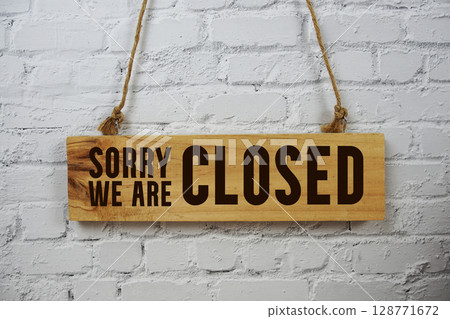 Sorry We're Close text on wooden sign hanging on white brick wall background Sorry We're Close text on wooden sign hanging on white brick wall background 128771672