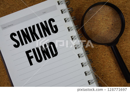 Sinking Fund text written on notebook paper with magnifying glass Sinking Fund text written on notebook paper with magnifying glass 128771697