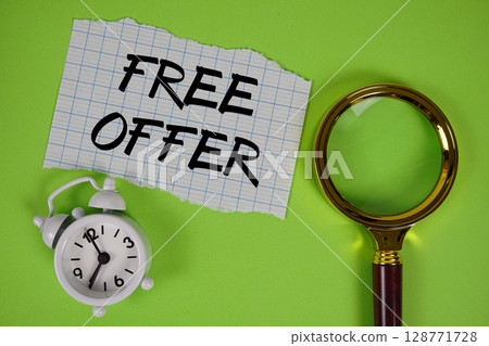 Free Offer text written on paper with magnifying glass and alarm clock 128771728