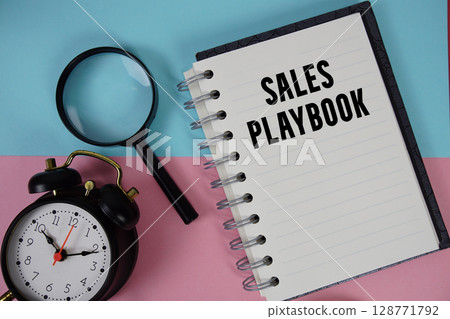 Sales Playbook text written on notebook paper with magnifying glass and alarm clock Sales Playbook text written on notebook paper with magnifying glass and alarm clock 128771792