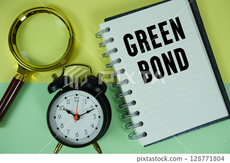Green Bond text written on notebook paper with magnifying glass and alarm clock 128771804