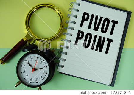 Pivot Point text written on notebook paper with magnifying glass and alarm clock 128771805