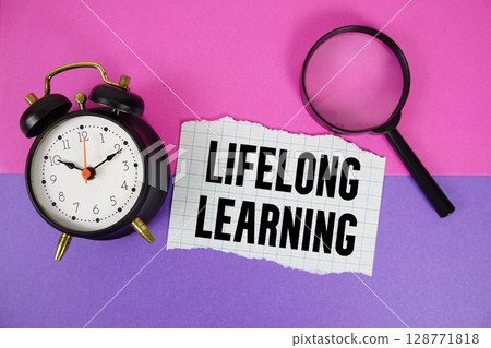 Lifelong Learning text written on notebook paper with magnifying glass and alarm clock Lifelong Learning text written on notebook paper with magnifying glass and alarm clock 128771818