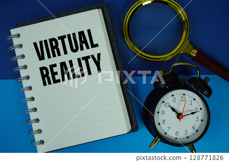 Virtual Reality text written on notebook paper with magnifying glass and alarm clock 128771826