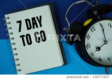 7 Day To go text written on notebook paper with alarm clock 128771827