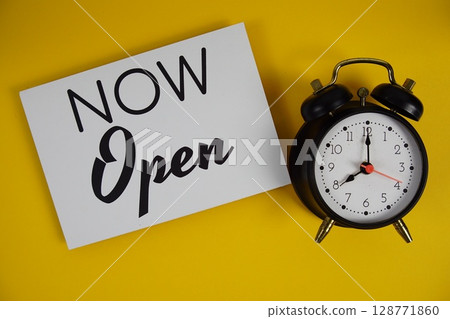 Now Open alphabet letters with alarm clock flat lay on yellow background 128771860
