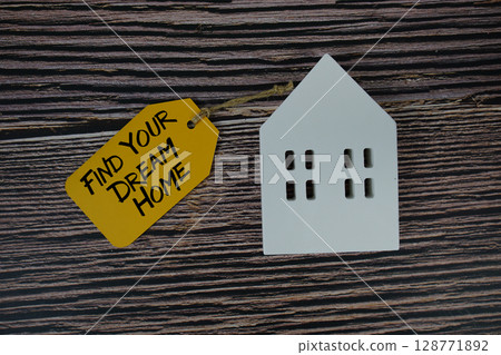 Find Your Dream Home text on price tag with white house model flat lay on wooden background Find Your Dream Home text on price tag with white house model flat lay on wooden background 128771892