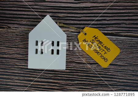 Homeland Security Investigations text on price tag with white house model flat lay on wooden background 128771895