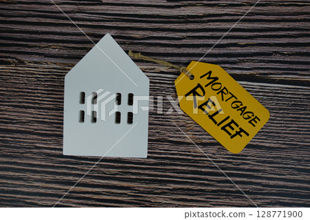 Mortgage Relief text on price tag with white house model flat lay on wooden background 128771900
