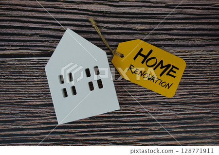 Home Renovation text on price tag with white house model flat lay on wooden background 128771911