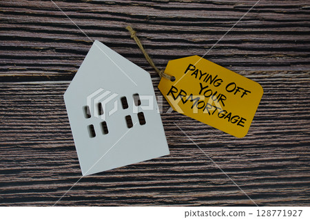 Paying Off Your Mortgage text on price tag with white house model flat lay on wooden background 128771927