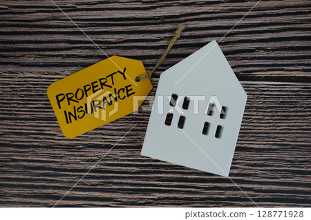 Property Insurance text on price tag with white house model flat lay on wooden background 128771928