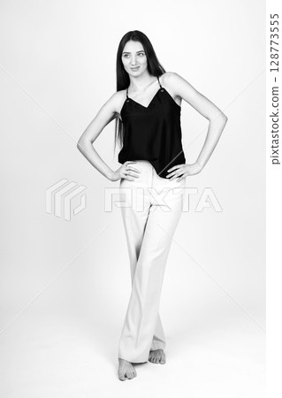 Beautiful woman with black blouse and white pants studio portrait 128773555