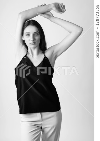 Beautiful woman with black blouse and white pants studio portrait 128773558