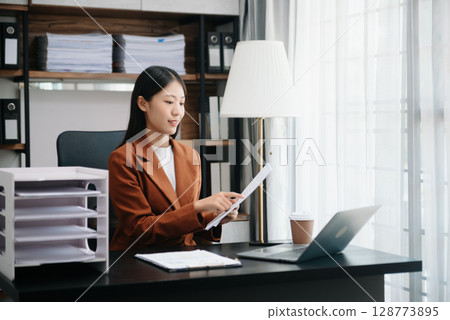 Business woman using tablet and laptop for doing math finance on an office desk, tax, report, accounting, statistics, and analytical research concept 128773895