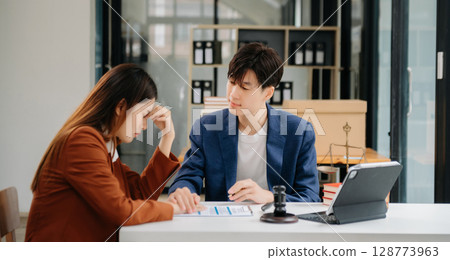 Business people compassionately holding hands and discussing contract papers with laptop and tabletat office 128773963