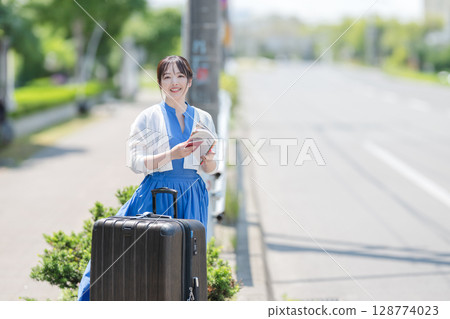 Woman with suitcase and guidebook 128774023