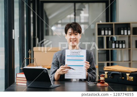 Asian female lawyer chatting online with client on laptop, smartphone discussing details of lawsuit. in modern office Asian female lawyer chatting online with client on laptop, smartphone discussing details of lawsuit. in modern office 128774055