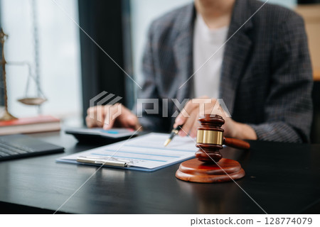 justice and law concept.law theme wooden desk, books, balance. Male judge in a courtroom the gavel,working with digital tablet computer on table justice and law concept.law theme wooden desk, books, balance. Male judge in a courtroom the gavel,working with digital tablet computer on table 128774079