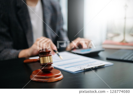 justice and law concept.law theme wooden desk, books, balance. Male judge in a courtroom the gavel,working with digital tablet computer on table justice and law concept.law theme wooden desk, books, balance. Male judge in a courtroom the gavel,working with digital tablet computer on table 128774080