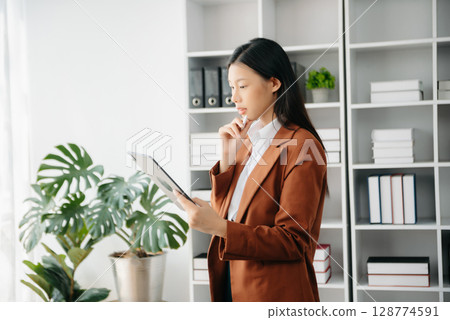 Beautiful Asian business woman typing laptop and tablet Placed at the table at the office Beautiful Asian business woman typing laptop and tablet Placed at the table at the office 128774591
