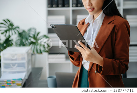 Businesswoman hand using laptop, tablet and smartphone in office. Digital marketing media mobile app and discussing plan new start up project. Finance task. 128774711