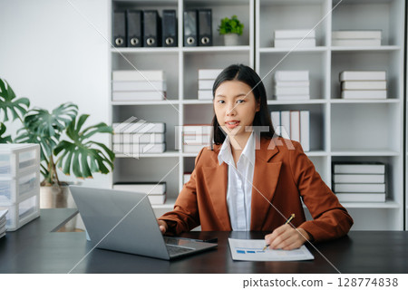 Beautiful Asian business woman typing laptop and tablet Placed at the table at the office 128774838