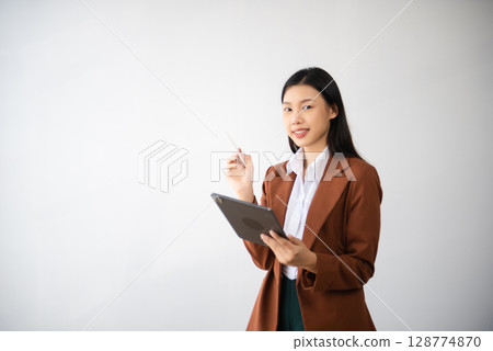 Portrait photo of young beautiful Asian woman feeling happy and holding smart phone, tablet and laptop with black empty screen on white background can use for advertising or product concept. 128774870