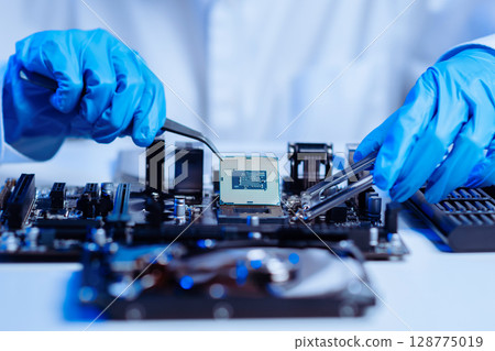 The technician is putting the CPU on the socket of the computer motherboard. electronic engineering electronic repair, electronics 128775019