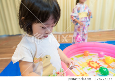幼稚園裡玩水溜溜球釣魚的小女孩 128775257