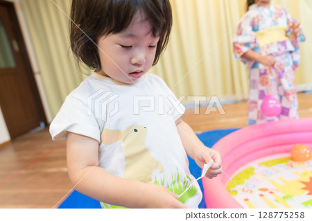 Toddler girl playing with water yo-yo fishing at nursery school Toddler girl playing with water yo-yo fishing at nursery school 128775258