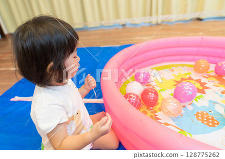 幼稚園裡玩水溜溜球釣魚的小女孩 128775262