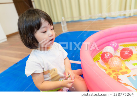 Toddler girl playing with water yo-yo fishing at nursery school Toddler girl playing with water yo-yo fishing at nursery school 128775264