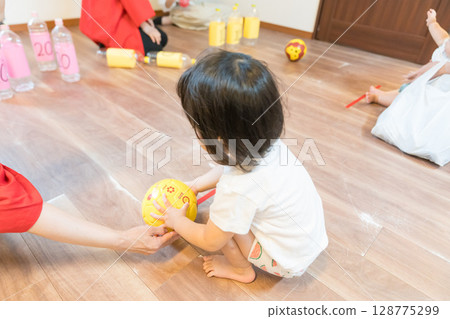 Toddler girl playing bowling game at nursery Toddler girl playing bowling game at nursery 128775299