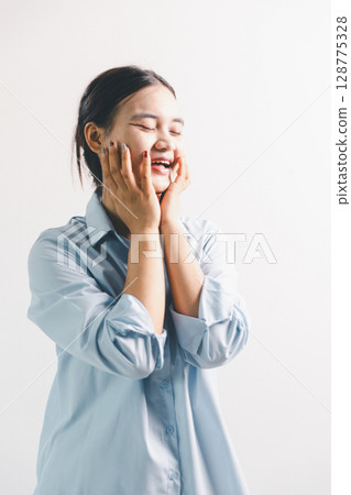Asian woman rejoicing, looking happy, champion, fist pump gesture, standing over white background. young woman had happy, positive expression on her face, highlighted by bright smile. 128775328