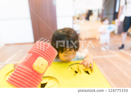 Toddler girl playing whack-a-mole at daycare Toddler girl playing whack-a-mole at daycare 128775350