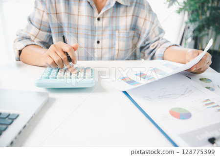 Accountant working on desk using calculator for calculate finance report in office. business finance, calculate tax by organizing financial documents, tracking income investment, accounting by hand. Accountant working on desk using calculator for calculate finance report in office. business finance, calculate tax by organizing financial documents, tracking income investment, accounting by hand. 128775399
